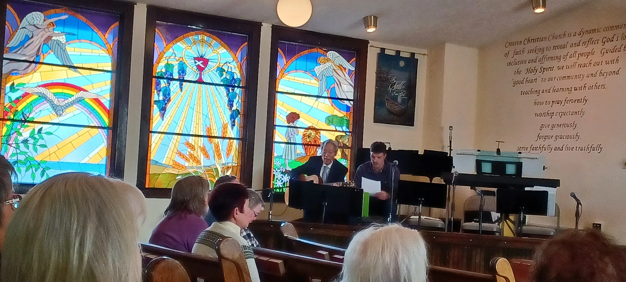 Pastor Jae Rhee leading worship beneath the stained-glass windows at Creston Christian Church